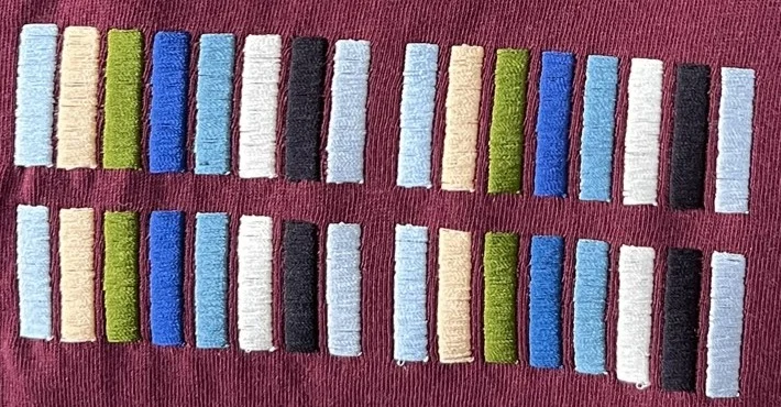 Photo d’atelier : barres de satin brodées sur un t-shirt, une par couleur de fil